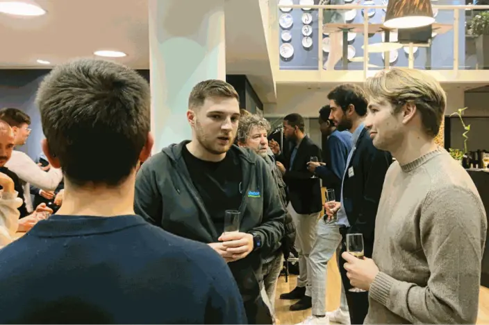 Des étudiants échangent dans une ambiance décontractée, avec une coupe de champagne, dans un moment informel et convivial.