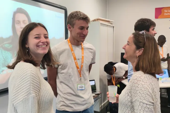Une entrepreneure échange avec deux étudiants autour d’un verre, dans une ambiance souriante et dynamique.